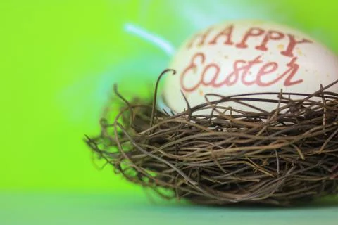An Easter egg with a inscription Happy Easter in a bird's nest, green background Stock Photos
