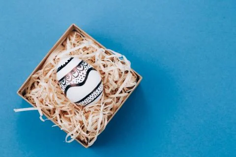 The Easter egg is painted in black and white, an abstraction, lies in a box. Stock Photos
