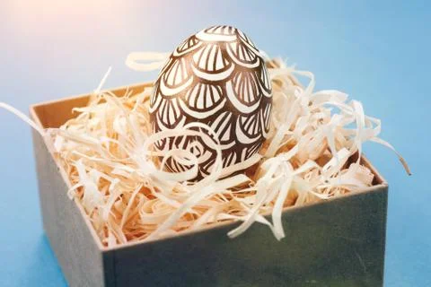 The Easter egg is painted in black and white, an abstraction, lies in a box. Stock Photos