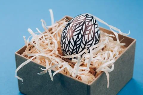 The Easter egg is painted in black and white, an abstraction, lies in a box. Stock Photos