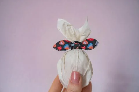 Easter egg in paper in the shape of a bunny with a bow. Symbol of Easter Stock Photos