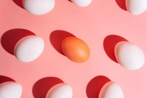 Easter egg pattern with one orange egg among white eggs on pink background 스톡 사진