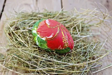Easter egg with a pattern of red flowers and green leaves in the hay on the Stock Photos