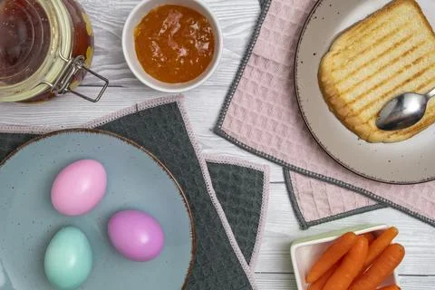 Easter egg in plate on a breakfast table with jam and pink white tulips. Stock Photos
