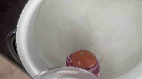 An Easter egg with a purple sleeve and white pattern is dipped into hot water Stock Footage 305462671