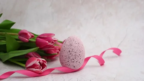 Easter egg with ribbon and pink tulips on light concrete background Stock Footage 234325948