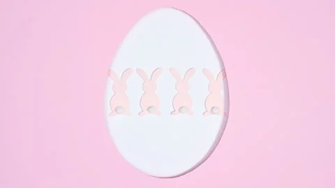 Easter egg shape frame with pastel pink rabbits on pink background. Stop motion Stock Footage 171361718