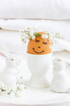 An Easter egg with a sweet  face and a wreath of flowers surrounded by cute.. Stock Photos
