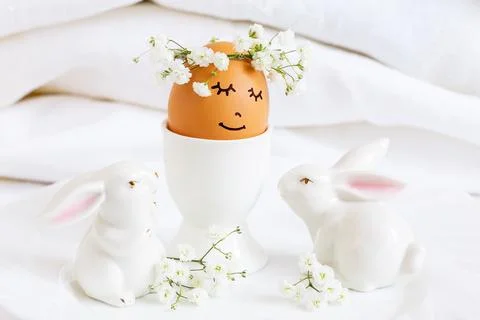 An Easter egg with a sweet  face and a wreath of flowers surrounded by  two.. Stock-Fotos
