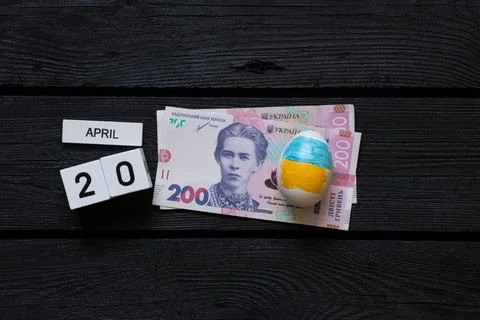 Easter egg with Ukrainian flag and 200 hryvnia bills and cubes with the date  Stock Photos