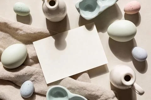 Easter eggs and ceramic vases arranged with a blank card and linen fabric Stock Photos