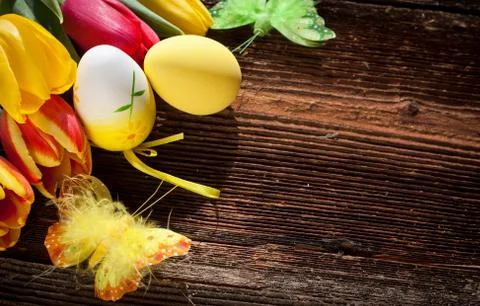 Easter eggs and fresh spring tulips on weathered wooden background Stock Photos