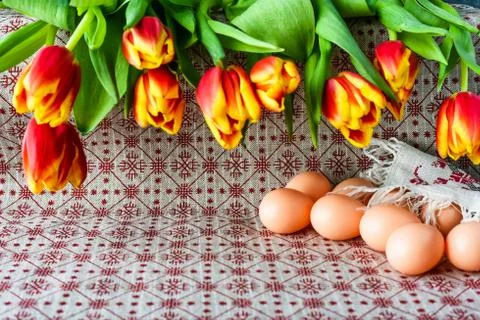 Easter eggs and fresh spring tulips on a tablecloth Stock Photos