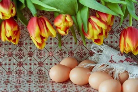 Easter eggs and fresh spring tulips on a tablecloth Stock Photos