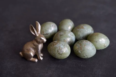 Easter eggs and metallic rabbit on dark background. Stock Photos