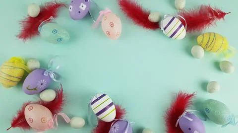 Easter eggs and pink feathers on a blue background. space for text. Stock Photos