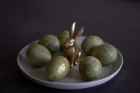 Easter eggs and rabbit figurine on white plate. Stock Photos