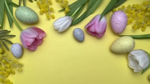 Easter eggs and spring flowers creating festive border on yellow background Stock Footage 305307285