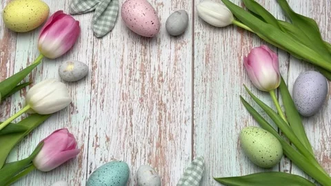 Easter eggs and tulips forming a border on rustic white wood Video stock 305531415