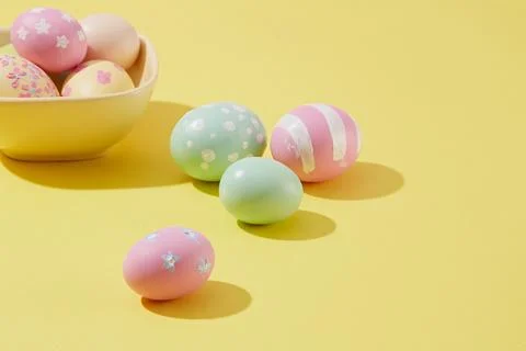 Easter eggs are painted with cute patterns and colors decorated on a yellow b Stock Photos