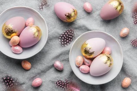 Easter eggs are painted with violet and gold paint on a gray linen background Stock Photos