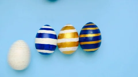 Easter eggs are rolling, knocking each other on blue table. Eggs trendy colored Stock Footage 126086101