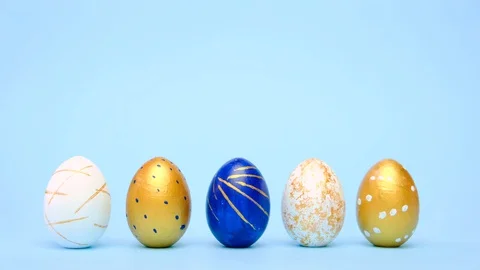 Easter eggs are rolling, knocking each other on blue table. Eggs trendy colored Stock Footage 127683936