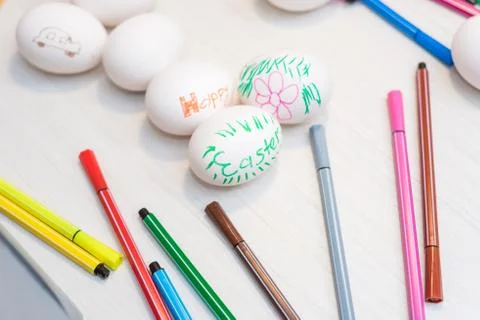 Easter eggs are on the table with colored felt-tip pens. Stock Photos