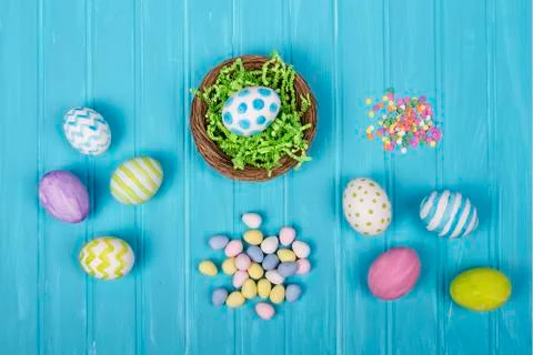 Easter eggs, basket, and candy on a blue background Stock Photos