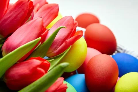 Easter Eggs in basket and spring flowers on white wooden table Stock Photos