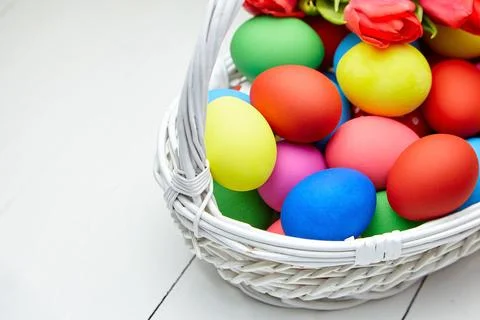 Easter Eggs in basket and spring flowers on white wooden table Stock Photos