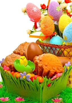 Easter eggs in the basket, chocolate eggs and muffins on the grass Stock Photos