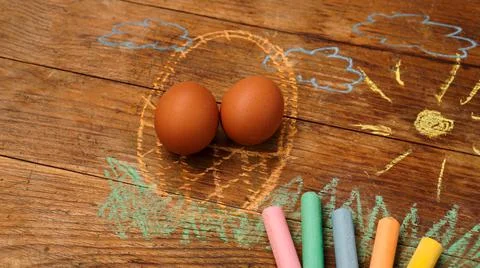 Easter eggs in a basket. Drawing with colored chalk on a wooden background Stock Photos