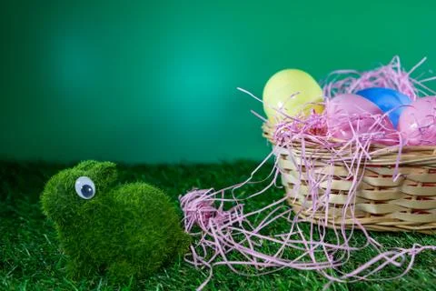Easter eggs on a basket with grass and a green rabbit made of grass with gree Stock Photos