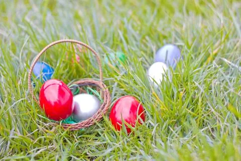 Easter eggs in a basket hidden in the grass Stock Photos