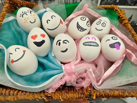 Easter eggs in a basket with painted faces and hearts instead of eyes Stock Photos