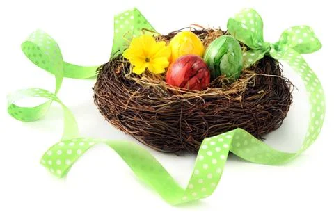 Easter eggs in basket with primula flower heads. ribbon around Stock Photos