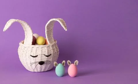 Easter eggs in a basket in the shape of an Easter Bunny. Festive decor on pur Фото