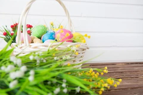 Easter eggs in basket on shelf in front of wooden wall. View with copy space Stock Photos