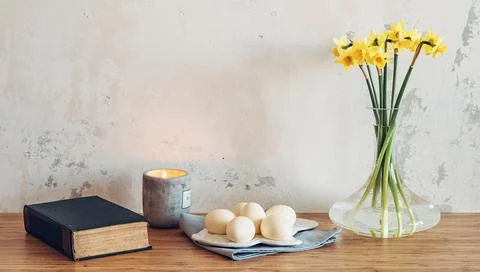 Easter eggs, bible and spring flowers on table against wall background Stock Photos