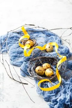 Easter Eggs in bird Nest. Quail easter eggs in nest on white table with cop.. Foto stock