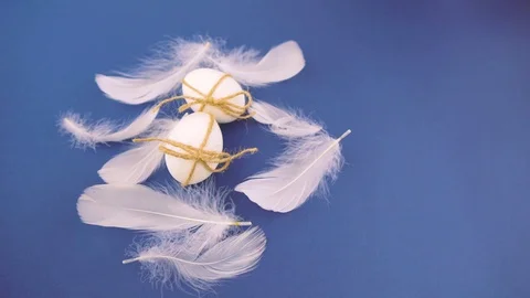 Easter eggs on a blue background tied with a felt ribbon with feathers. Stock Footage 122312420