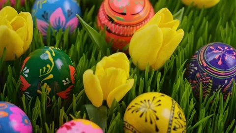 Easter eggs in bold, hand-painted designs lie among green grass and tulips... Stock Footage 300958409