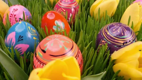 Easter eggs in bold, hand-painted designs lie among green grass and tulips... Stock Footage 301351009