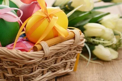 Easter eggs with bows in the basket over floral background Stock Photos