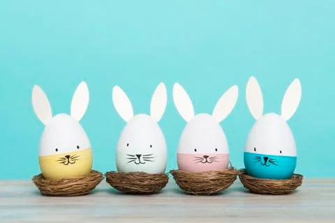 Easter eggs with bunny faces in nest on a blue background Stock Photos