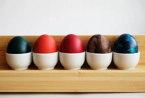 Easter eggs on ceramic stands on bamboo tray on a white background Foto stock