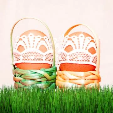 Easter eggs in colored baskets on grass and on a blurry background Stock Photos