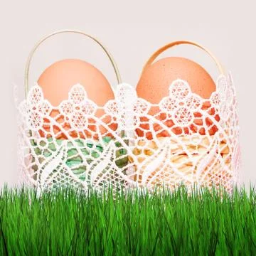 Easter eggs in colored baskets on grass and on a blurry background Stock Photos