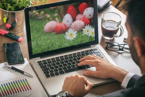Easter eggs on a computer screen. Man working in his office, view from above Foto stock